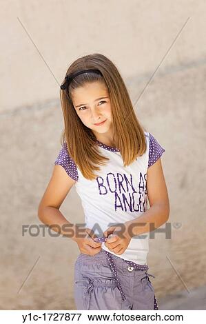 Stock Photo - Young girl is adjusting a hem of her t-shirt. Fotosearch
