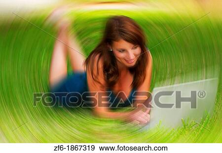 Stock Photo - Young girl laying in yard emailing and searching web having fun with Facebook with friends. Fotosearch