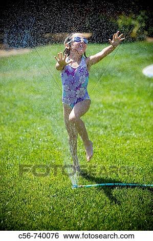 Young girl leaps through yard sprinkler View Large Photo Image Stock Photograph - Young girl leaps through yard sprinkler. Fotosearch