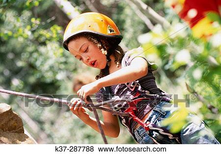 Young girl learning to tie knot before climbing rock face at rock climbing school View Large Photo Image Stock Photo - Young girl learning to tie knot before climbing rock face at rock climbing school. Fotosearch