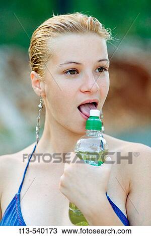 Stock Image - Young girl licking plastic bottle tip. Fotosearch