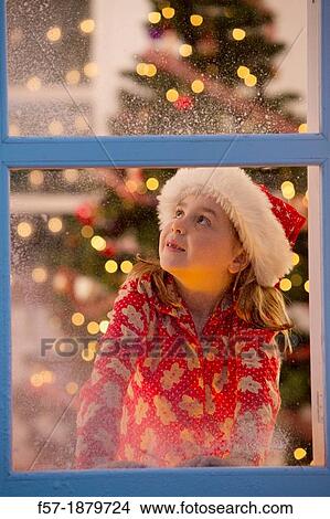Young girl looking out of the window waiting for Santa to arrive View Large Photo Image Picture - Young girl looking out of the window waiting for Santa to arrive. Fotosearch