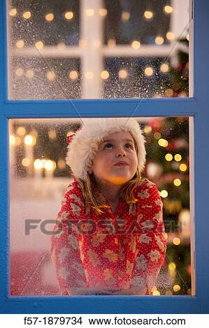 Young girl looking out of the window waiting for Santa to arrive View Large Photo Image Picture - Young girl looking out of the window waiting for Santa to arrive. Fotosearch