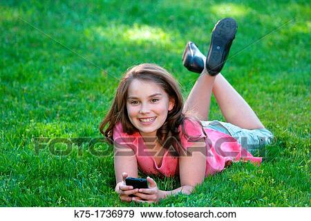 young girl lying on lawn listening to music View Large Photo Image Stock Photo - young girl lying on lawn listening to music. Fotosearch