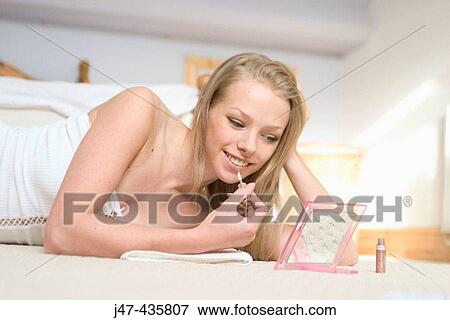 Young girl lying on the floor looking into a mirror smiling View Large Photo Image Stock Photo - Young girl lying on the floor looking into a mirror smiling. Fotosearch