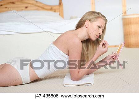 Stock Photograph - Young girl lying on the floor looking into a mirror. Fotosearch