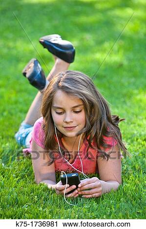Young girl outdoors listening to music View Large Photo Image Stock Image - Young girl outdoors listening to music. Fotosearch