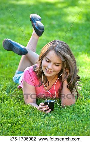 Young girl outdoors listening to music View Large Photo Image Stock Image - Young girl outdoors listening to music. Fotosearch