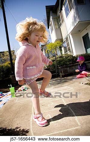Young girl playing hopscotch infront of her appartment in the sun. Sister playing on the sidewalk behind her. View Large Photo Image Stock Image - Young girl playing hopscotch infront of her appartment in the sun. Sister playing on the sidewalk behind her.. Fotosearch