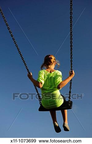 Young girl playing on a swing in a playground on a sunny summer afternoon, UK View Large Photo Image Stock Photo - Young girl playing on a swing in a playground on a sunny summer afternoon, UK. Fotosearch