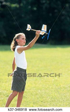 Young girl playing with model airplane in field dreaming about being a pilot. View Large Photo Image Stock Photo - Young girl playing with model airplane in field dreaming about being a pilot.. Fotosearch