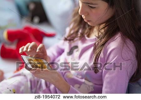 Young girl playis games on mobile device in bed. View Large Photo Image Stock Image - Young girl playis games on mobile device in bed.. Fotosearch
