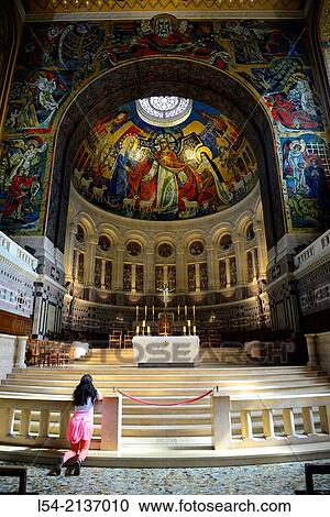 Stock Image - Young Girl Praying Kneeling National Shrine of St. Therese Lisieux France Little Flower Basilica Church Europe.. Fotosearch