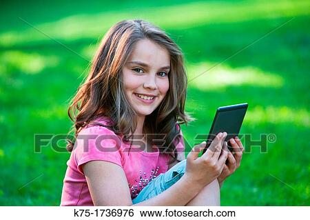 Stock Photograph - Young girl reading e-reader. Fotosearch