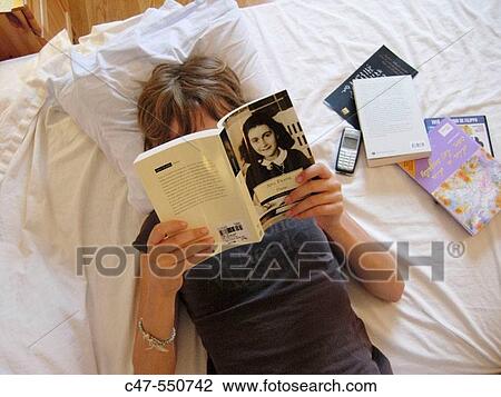 Stock Image - Young girl reading the Diary of Anne Frank. Fotosearch