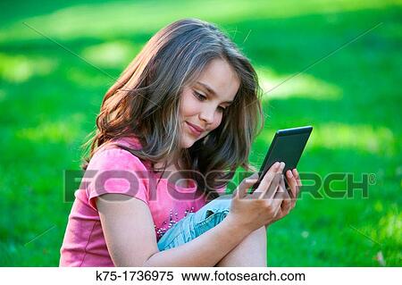 Young girl reading with e-reader View Large Photo Image Stock Photography - Young girl reading with e-reader. Fotosearch