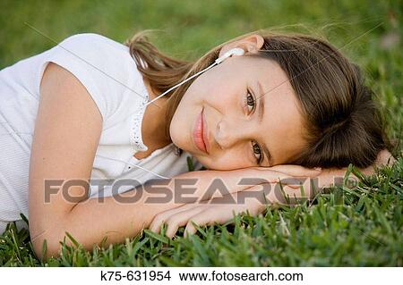 Young girl relaxing on lawn listening to music View Large Photo Image Picture - Young girl relaxing on lawn listening to music. Fotosearch