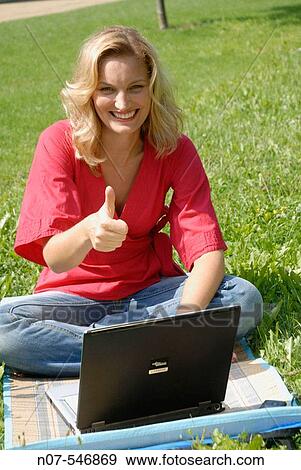 Young girl relaxing with a laptop on field View Large Photo Image Stock Photo - Young girl relaxing with a laptop on field. Fotosearch