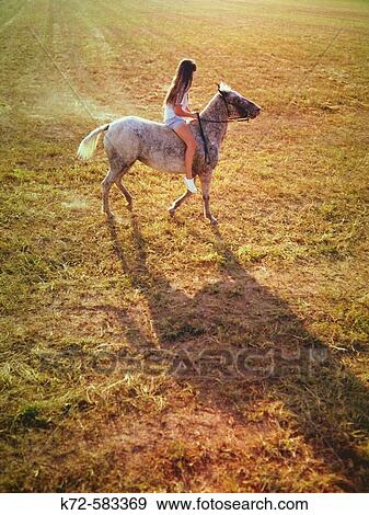 Stock Photo - Young girl riding horse. Fotosearch