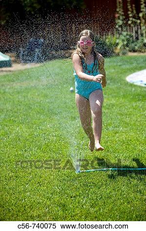 Stock Photography - Young girl runs through yard sprinkler. Fotosearch