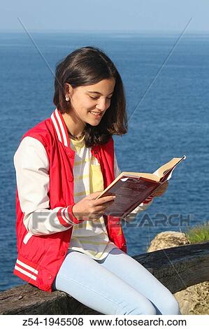 Young girl sitting near the sea, reading a book, Spain. View Large Photo Image Stock Photo - Young girl sitting near the sea, reading a book, Spain.. Fotosearch