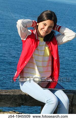 Stock Photo - Young girl sitting near the sea with a digital tablet in her legs, Bat of Biscay, Spain.. Fotosearch