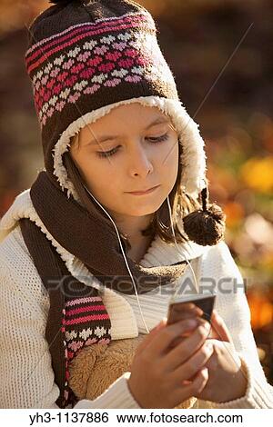 Stock Photograph - Young girl smiling at the camera while listening music with her iPod. Fotosearch