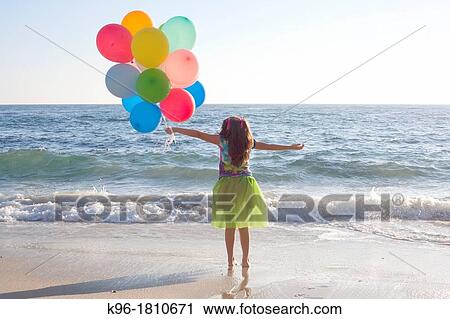 young girl standing at ocean with balloons View Large Photo Image Stock Image - young girl standing at ocean with balloons. Fotosearch