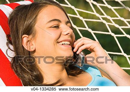 Stock Photography - Young girl talking on her cell phone in a hammock, Germany, Europe. Fotosearch