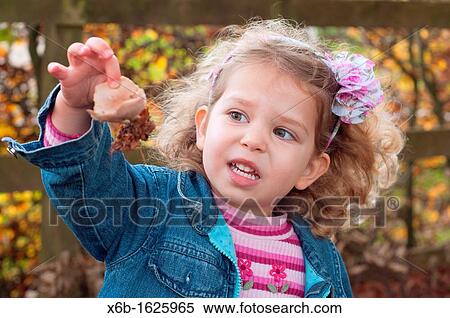 Stock Photography - Young girl, three years old, outside during Autumn marvelling at nature and fungi mushroom she has found.. Fotosearch