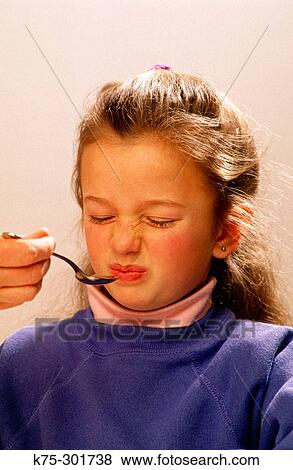 Stock Photo - young girl unhappy about taking her medicine. Fotosearch