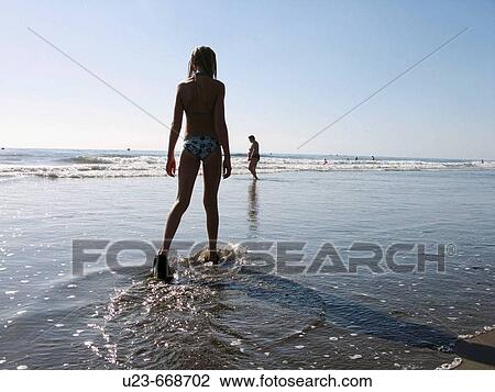 Stock Image - Young girl walking in the water's edge. Atlantic ocean.. Fotosearch
