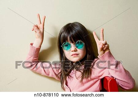 Stock Image - Young girl wearing green colored sunglasses.. Fotosearch