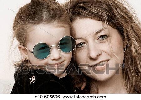 Young girl, wearing sunglasses, sitting with her mother. View Large Photo Image Stock Photograph - Young girl, wearing sunglasses, sitting with her mother.. Fotosearch