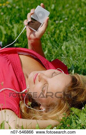 Stock Photograph - Young girl with a red dress enjoying mp3 music and relaxing. Fotosearch