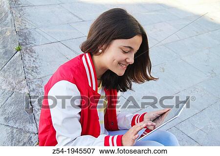 Stock Photo - Young girld looking at the screen of a touchpad, Spain.. Fotosearch