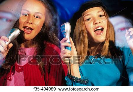 Stock Photo - Young girls having fun with sing along with karaoke machine. Fotosearch