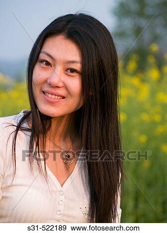 Stock Photo - Young good looking asian (chinese) girl enjoying the outdoors in a rape field. Fotosearch