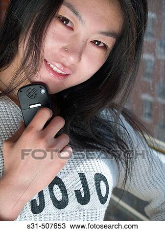 Stock Image - Young good looking asian female holding a cell phone. Fotosearch