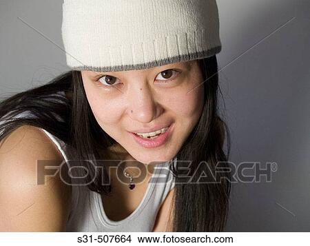 Picture - Young good looking asian girl wearing a winter hat. Fotosearch