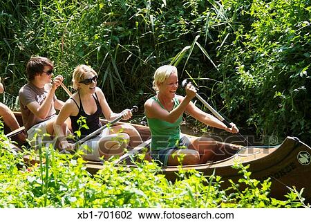 Young group of people canoeing on a small brook near Celle, Lower Saxony, Germany View Large Photo Image Stock Image - Young group of people canoeing on a small brook near Celle, Lower Saxony, Germany. Fotosearch