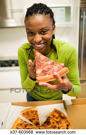 Young Haitian woman eating pizza in modern kitchen. View Large Photo Image Stock Photo - Young Haitian woman eating pizza in modern kitchen.. Fotosearch