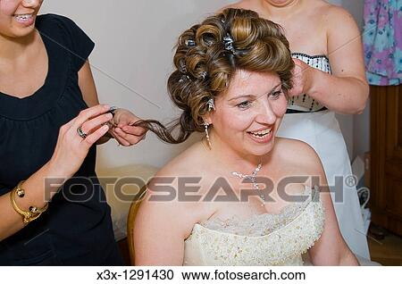 Stock Image - Young happy bride getting hair curled. Fotosearch