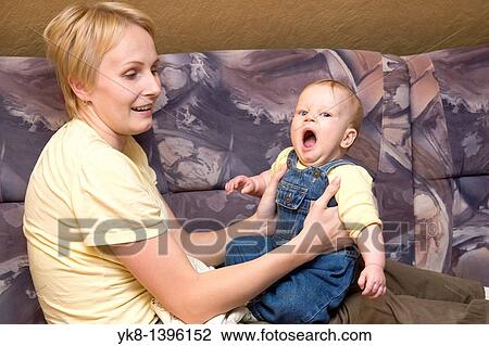 Young Happy Mother Sitting and Holding Yawning Infant Baby View Large Photo Image Stock Image - Young Happy Mother Sitting and Holding Yawning Infant Baby. Fotosearch