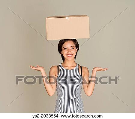 Young happy woman balance cardboard box on her head. View Large Photo Image Picture - Young happy woman balance cardboard box on her head.. Fotosearch