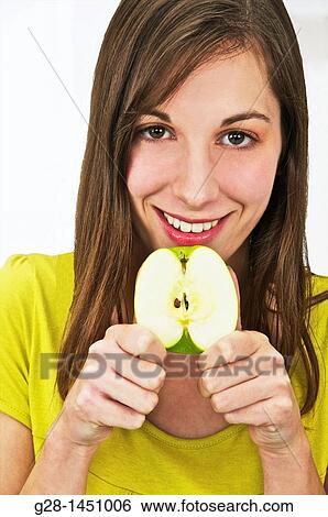 Young Happy woman holding a half green apple View Large Photo Image Stock Photograph - Young Happy woman holding a half green apple. Fotosearch