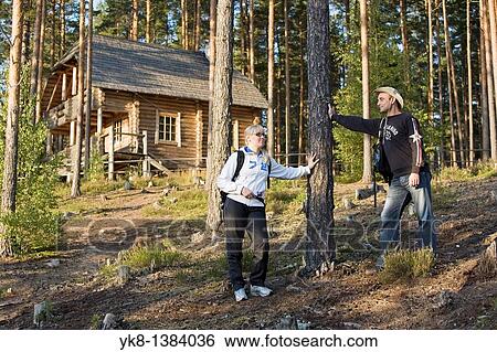 Stock Photograph - Young Hiking Couple Standing in Forest by Blockhouse in Meenikunno Landscape Reserve, Estonia. Fotosearch