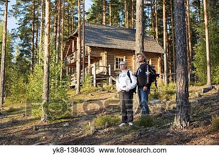 Stock Photography - Young Hiking Couple Standing in Forest by Blockhouse in Meenikunno Landscape Reserve, Estonia. Fotosearch