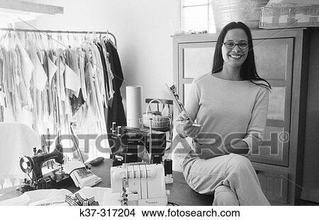 Picture - Young hispanic fashion designer starting up her business in her home garage. Fotosearch