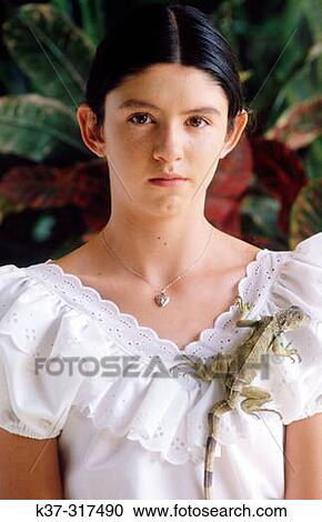 Stock Image - Young hispanic girl wearing white blouse and pet iguana. Fotosearch